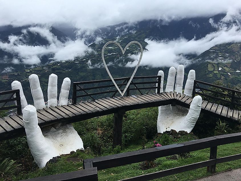 A mountainside boardwalk lookout supported by giant, white, artificial hands.