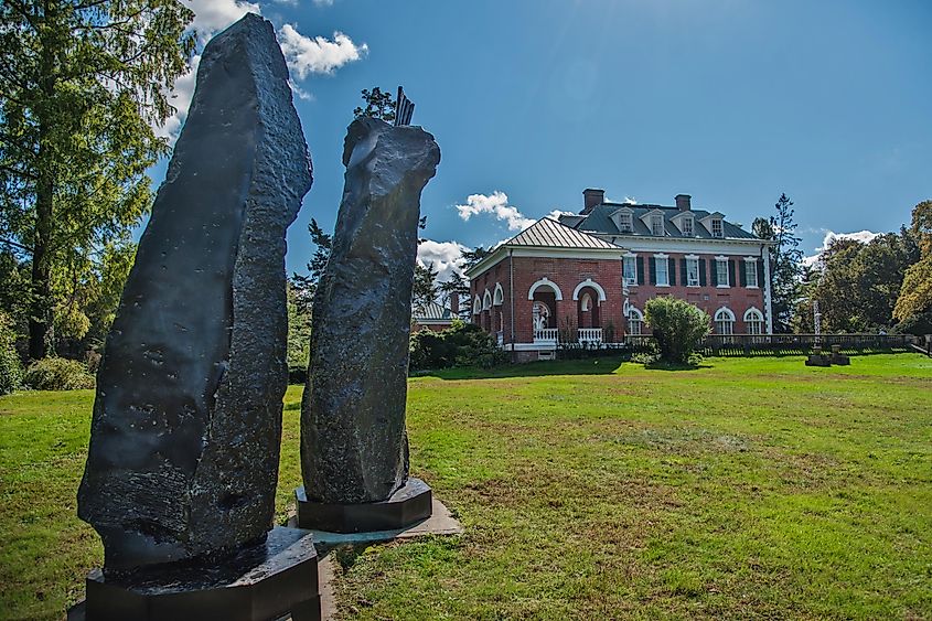 A distance view of the building of Nassau county museum of art in William Cullen Bryant Preserve park, with the statue of the king and queen