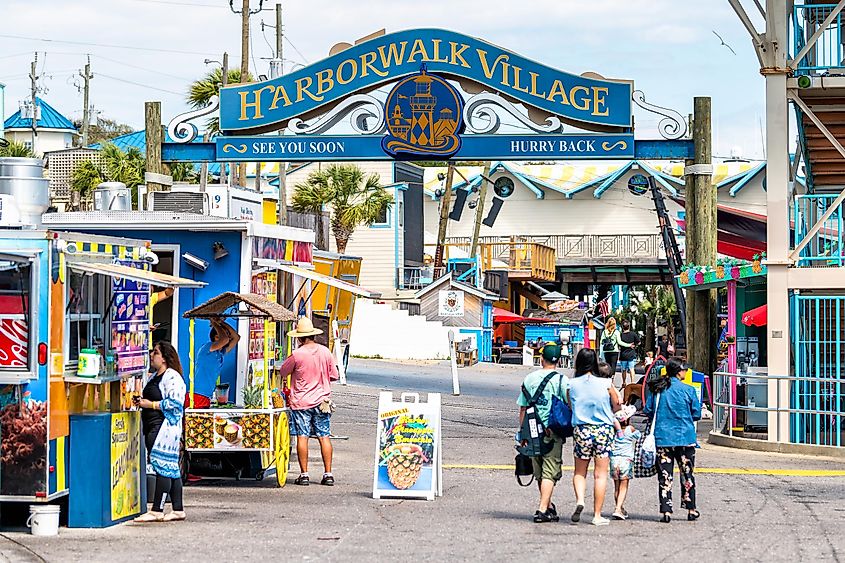 Destin, USA - April 24, 2018: Sign for Harborwalk Village in Emerald Grande Coast in Florida Panhandle with people walking and shopping, buying food in cafe, street vendor restaurants.