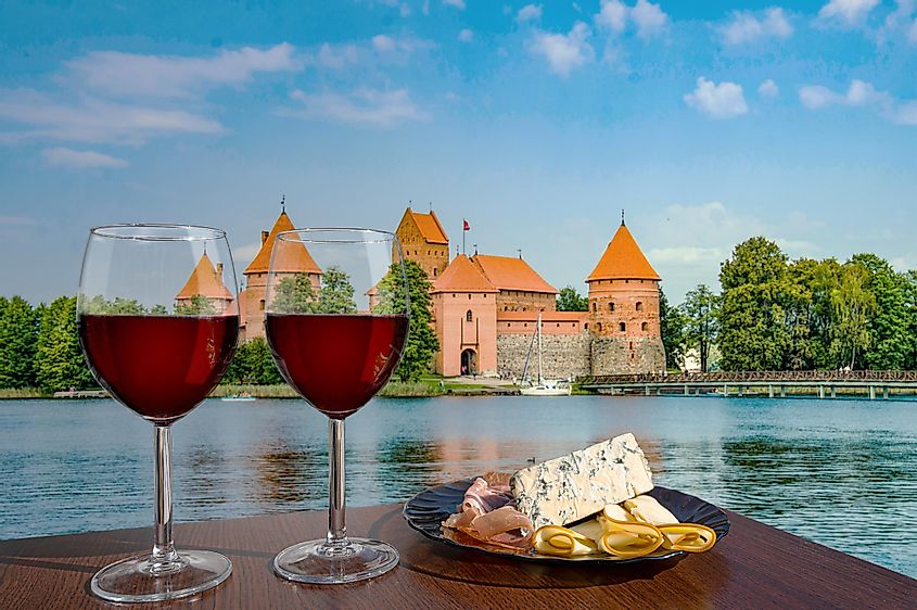 Two glasses of red wine with cheese and meat snacks with view of Trakai Island Castle near Vilnius, Lithuania. 
