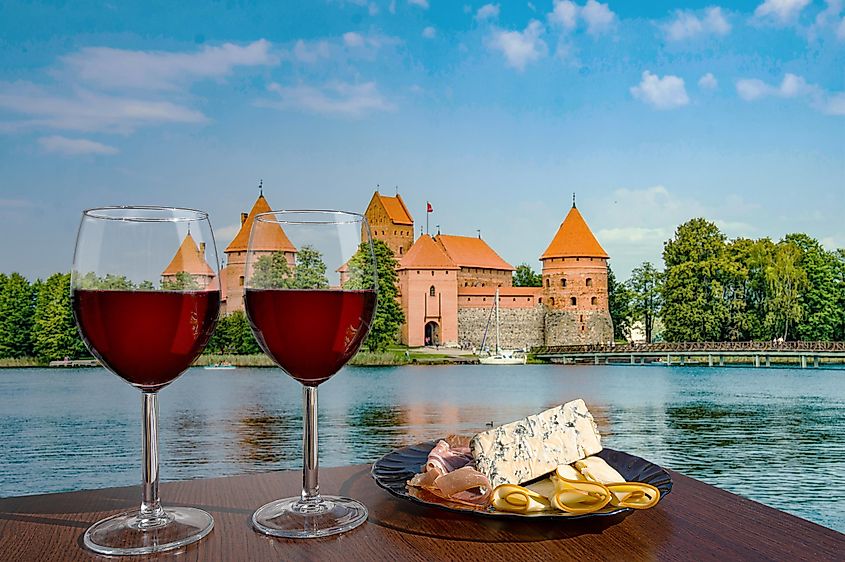 Two glasses of red wine with cheese and meat snacks with view of Trakai Island Castle near Vilnius, Lithuania. 