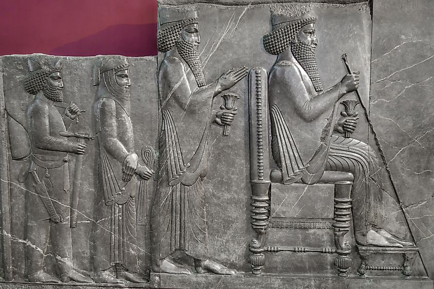 Ancient Persian relief from the 5th century BC. Depicts King Xerxes on his throne. Behind him stands the heir prince, the high priest and a warrior from the Immortal Guard. Shot in Tehran, Iran. Via Shutterstock / Poliorketes