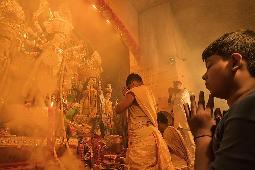 oung Hindu Priest worshipping Goddess Durga under holy smoke, Durga Puja festival ritual. - shot at night under colored light. Festival of Hinduism.