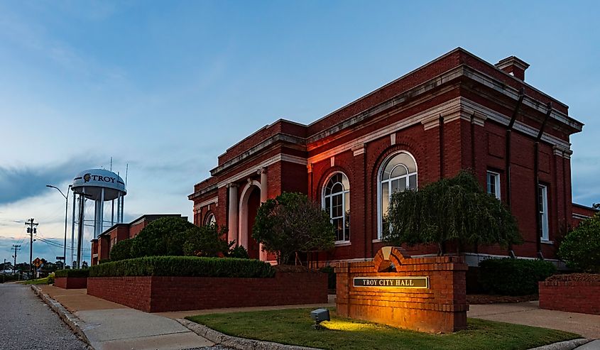 Troy City Hall illuminated during blue hour with water tower in distance. 