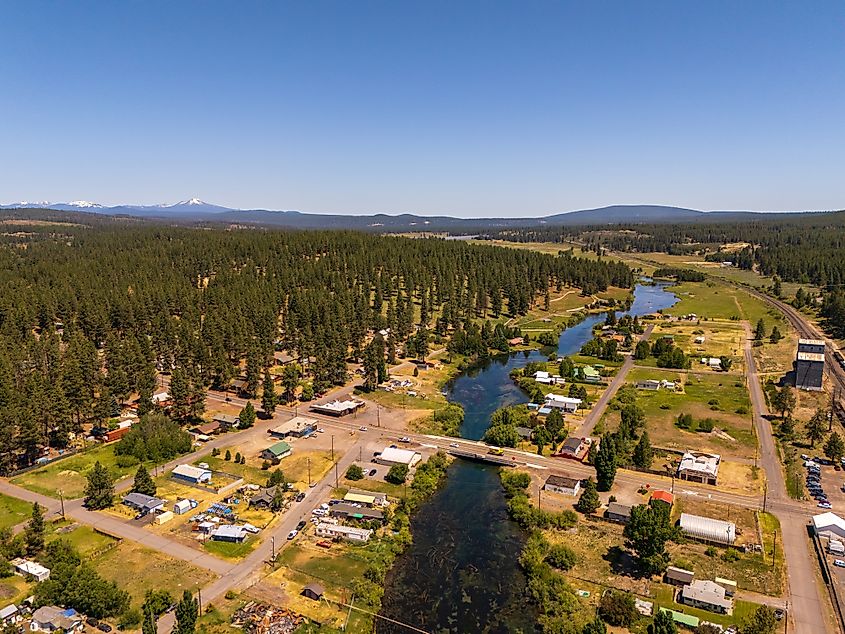 Aerial view of Chiloquin, Oregon, showing the clear Williamson River, railroad tracks, small businesses, and homes in the Pacific Northwest.