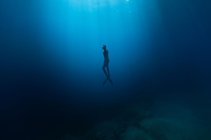 Freediver Swimming in Deep Sea With Sunrays.