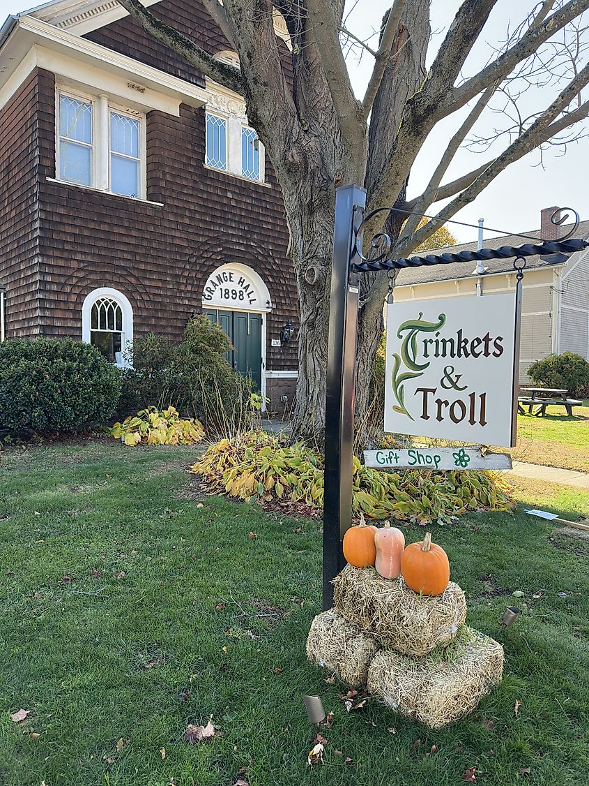 Sign for Trinkets and Troll Gift Shop in historic Grange Hall building.