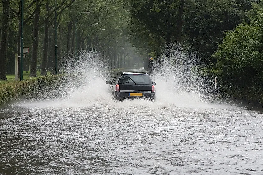 A car driving through a flooded street in the Netherlands.