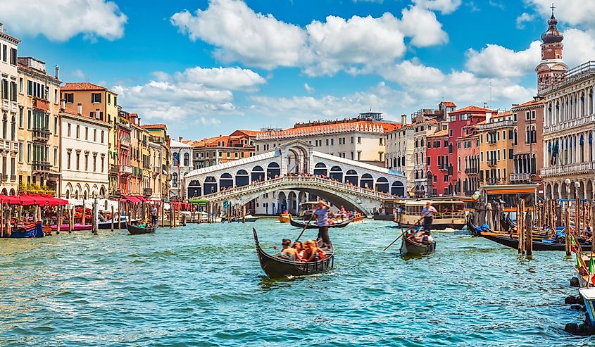 Bridge Rialto on Grand canal famous landmark panoramic view Venice Italy with blue sky white cloud and gondola boat water.