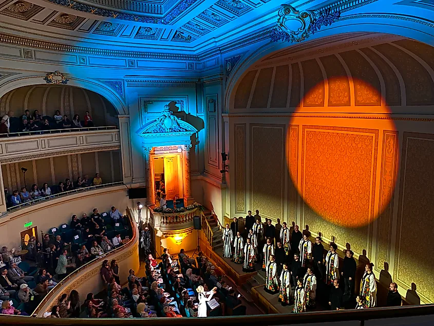 A choir sings to a large, ornate theater.