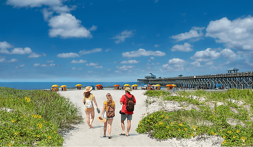 Family relaxing on the beautiful beach, People enjoying summer vacation by the ocean. Family walking on the beach. Cloudy sky and pier in the background. Folly Beach, South Carolina