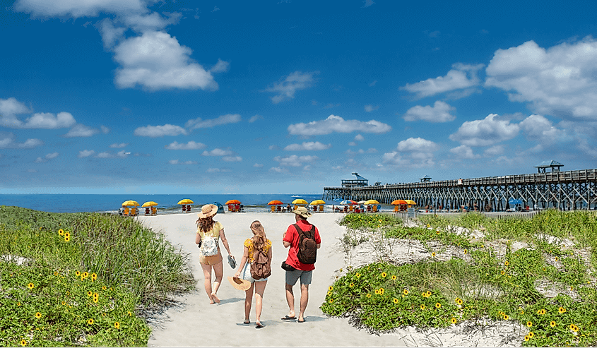 Family relaxing on the beautiful beach, People enjoying summer vacation by the ocean. Family walking on the beach. Cloudy sky and pier in the background. Folly Beach, South Carolina 