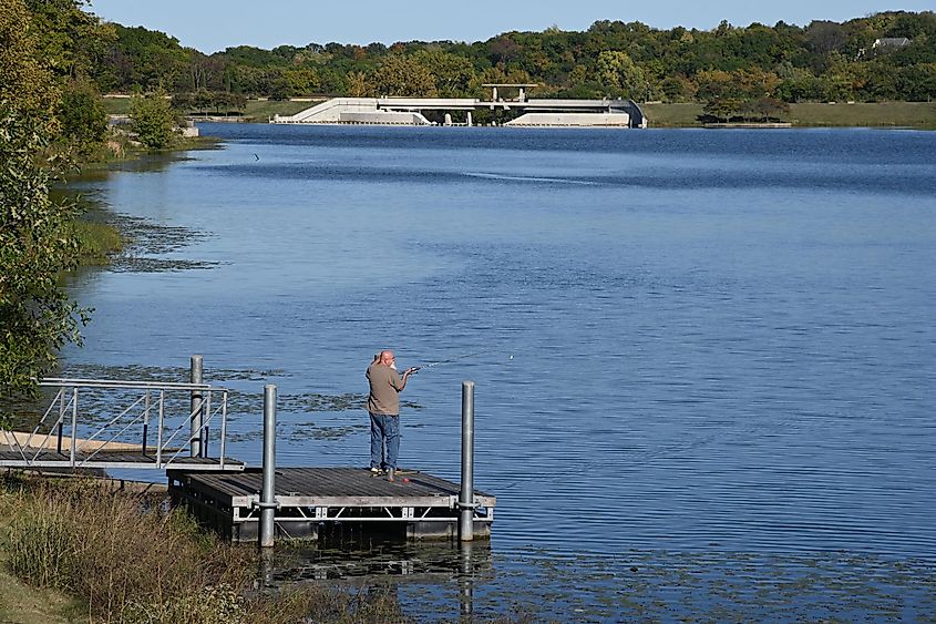 A man standing on the deck and fishing at Black Hoof Park Dam in Lenexa, Kansas