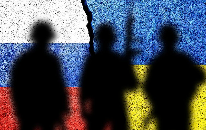Flag of Russia and Ukraine painted on a concrete wall with soldiers shadows