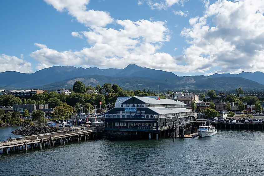 View of city and Olympic Mountains under bright summer cloudscape from ferry in harbor on sunny summer afternoon in Port Angeles, Washington.