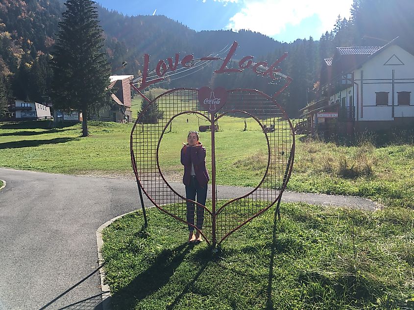 A woman doing a kiss pose through a heart-shaped "Love Lock"
