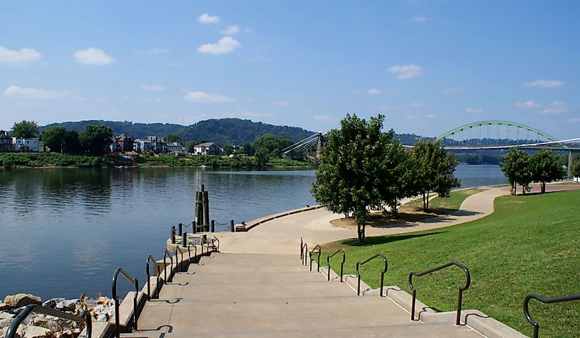 Wide steps lead down to the river walk along the Ohio River in Wheeling, West Virginia on a summer day, looking north toward the bridge to Ohio.