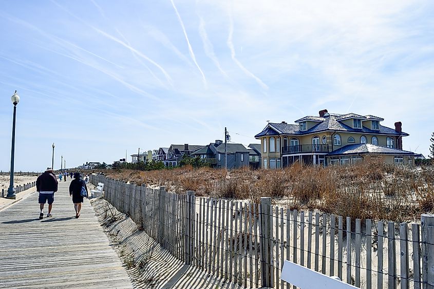 Rehoboth Beach: Sunny day with people walking along the boardwalk near beautiful houses.