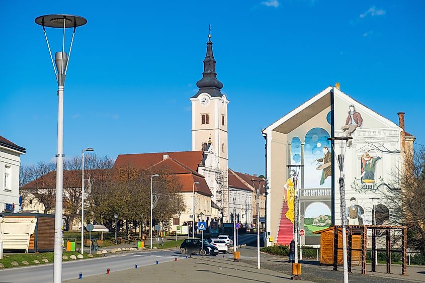 The church tower rises above a street scene, while a vibrant mural decorates a nearby building in Križevci. (Editorial credit: Ivan Klindic / Shutterstock.com)