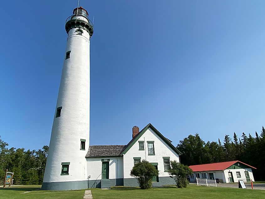 A tall, sheet-white lighthouse standing on a well kept lawn. 