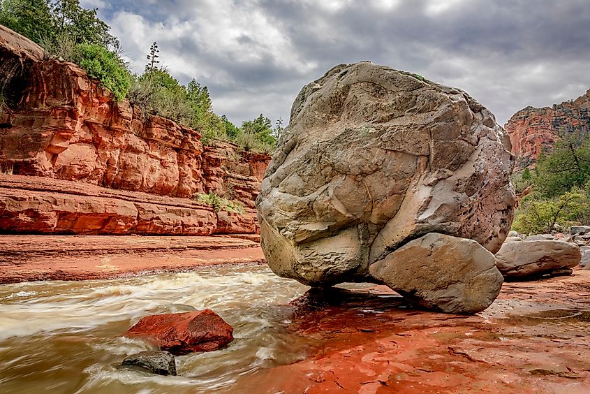 A giant gray boulder sits at the edge of Oak Creek at Slide Rock State Park near Sedona Arizona.