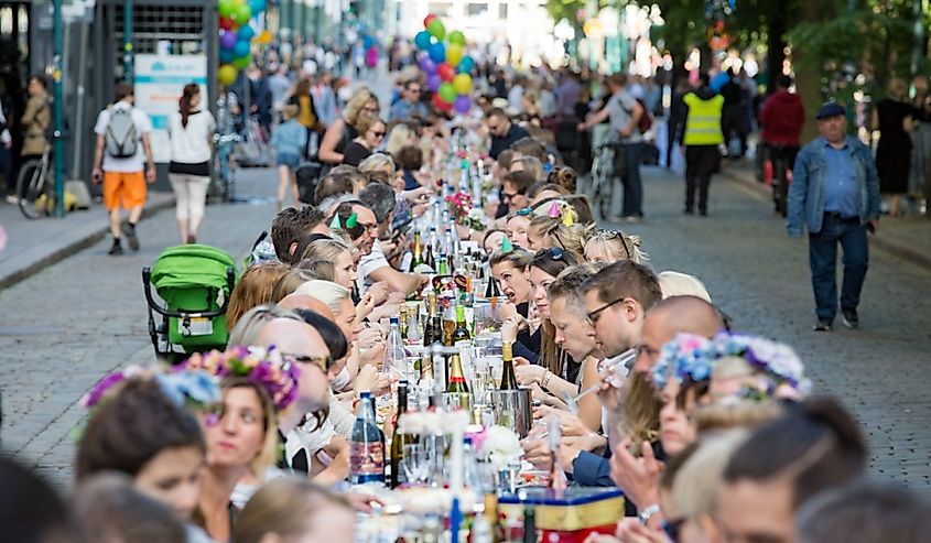 Long table with lots of people eating and drinking together. The Day of City Celebration in centre of Helsinki.