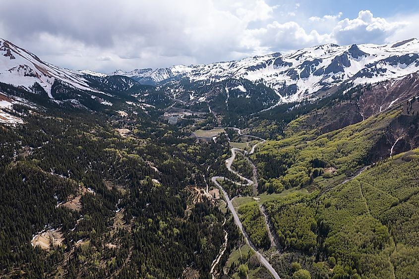 Aerial view of the snow-capped green mountains with winding road in the San Juan Mountains along the million dollar highway from Ouray to Silverton.