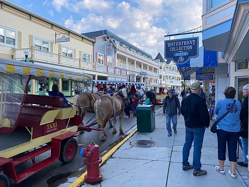 Crowds and horse-drawn carriages gather on the street before the Victorian structures of Mackinac Island.