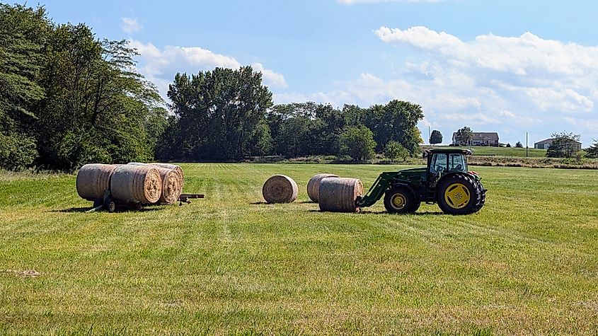 A tractor moves bales of hay on rural field in Tuscola, Illinois