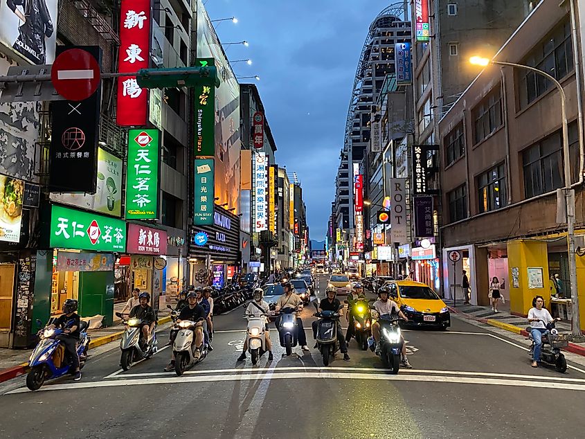 Motorist wait at an intersection backlit by neon signs in the heart of Taipei, Taiwan
