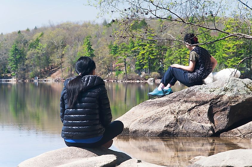 Two women sitting on rock enjoying the tranquil waters of Pawtuckaway Lake in Nottingham New Hampshire.