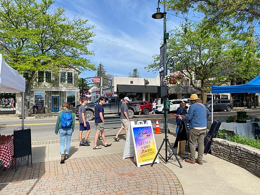 A street musician plays to the passing crowds at a pop-up farmers market.