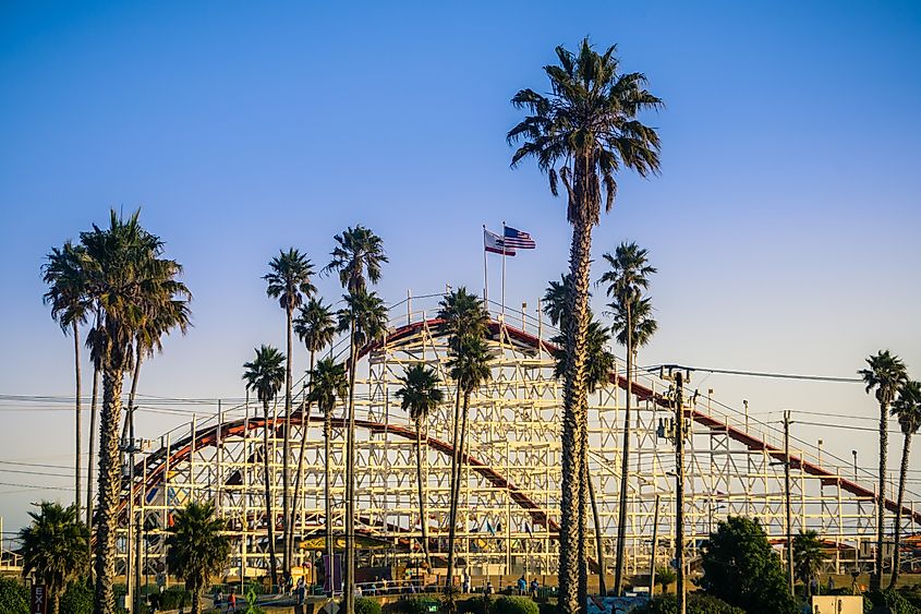 The Giant Dipper Roller coaster in Santa Cruz Beach Boardwalk amusement park at sunset, California.