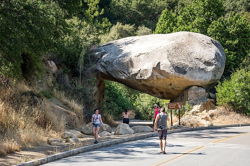 Giant natural stone arch Tunnel rock and walking tourists near the entrance to Sequoia National Park in California.
