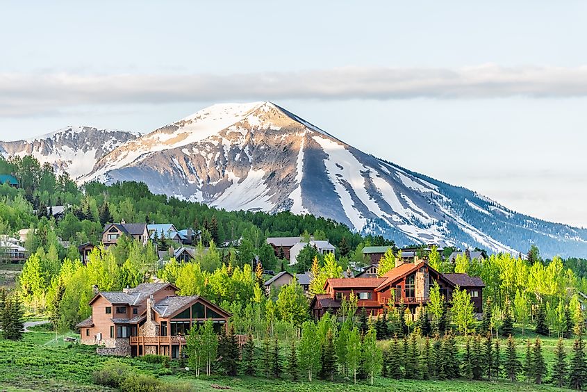 Mount Crested Butte, Colorado village in summer with colorful sunrise by wooden lodging houses on hills