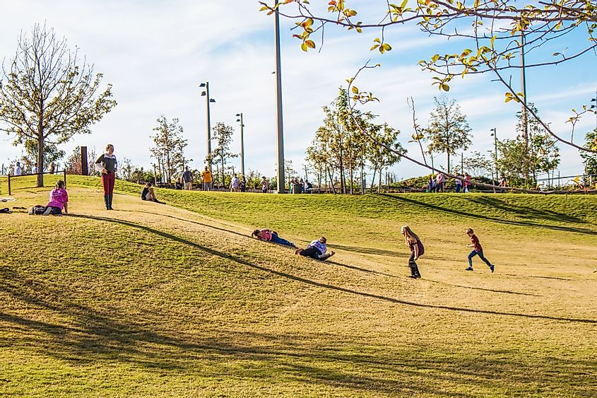 Kids rolling down a grassy hill in the Gathering Place Park in Tulsa, Oklahoma