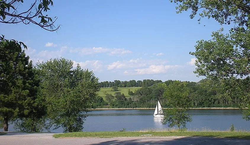 Sail boat on Glenn Cunningham Lake with green trees surrounding