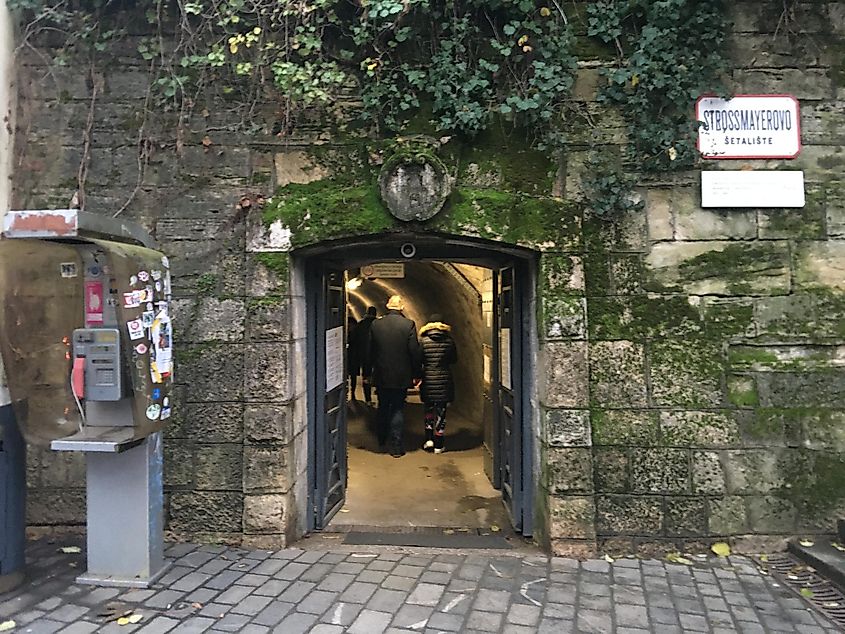 An old phone booth next to a mossy stone wall with a tunnel leading into it