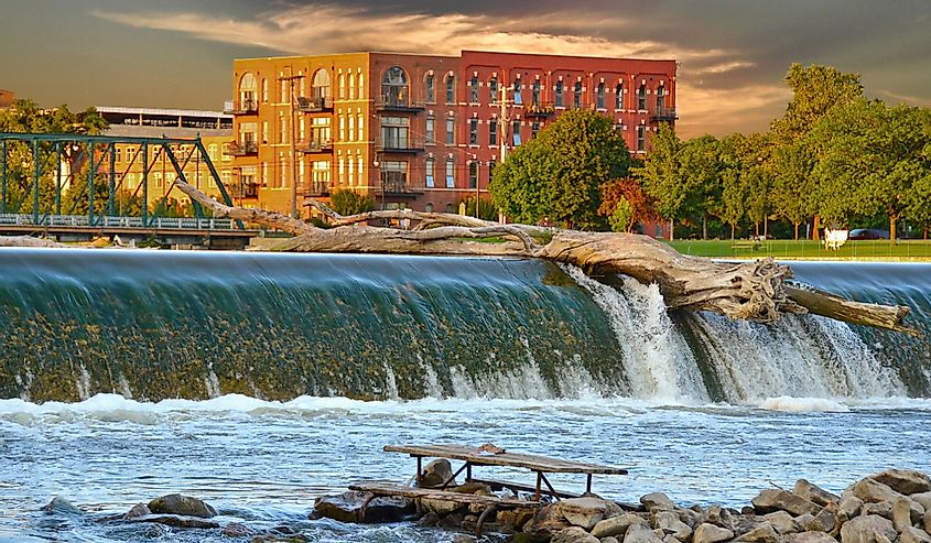 driftwood log on top of dam on the Grand river in grand rapids, michigan with a red brick building in the backdrop