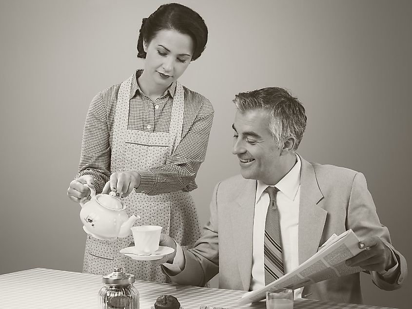 1950s beautiful woman serving tea for breakfast to her smiling husband