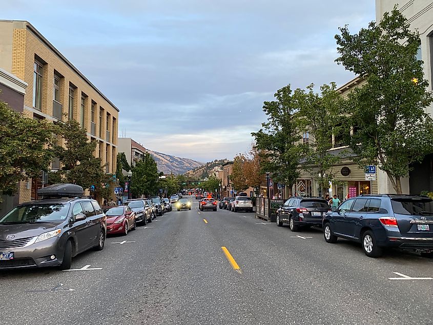 Evening descends on a small town main street, with the cliffs of the Columbia River Gorge looming in the background.