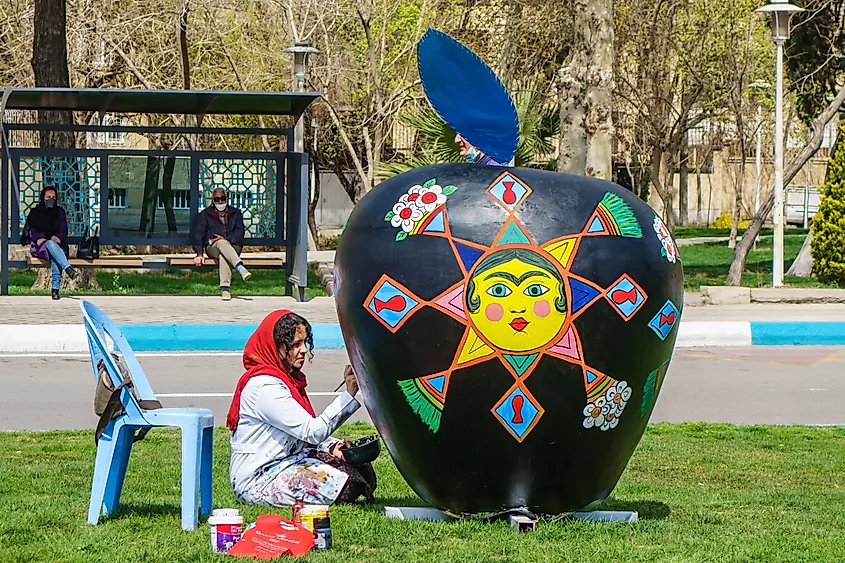 Young talented artist decorates street figure for traditional Nowruz festival celebration, Isfahan, Iran. Editorial credit: Poliorketes / Shutterstock.com