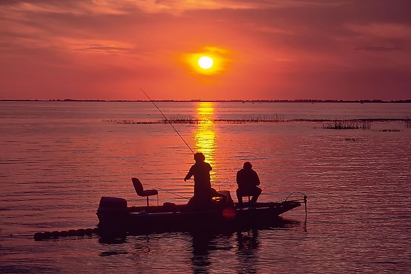 People in silhouette Bass Fishing at sunset on Lake Okeechobee FL .