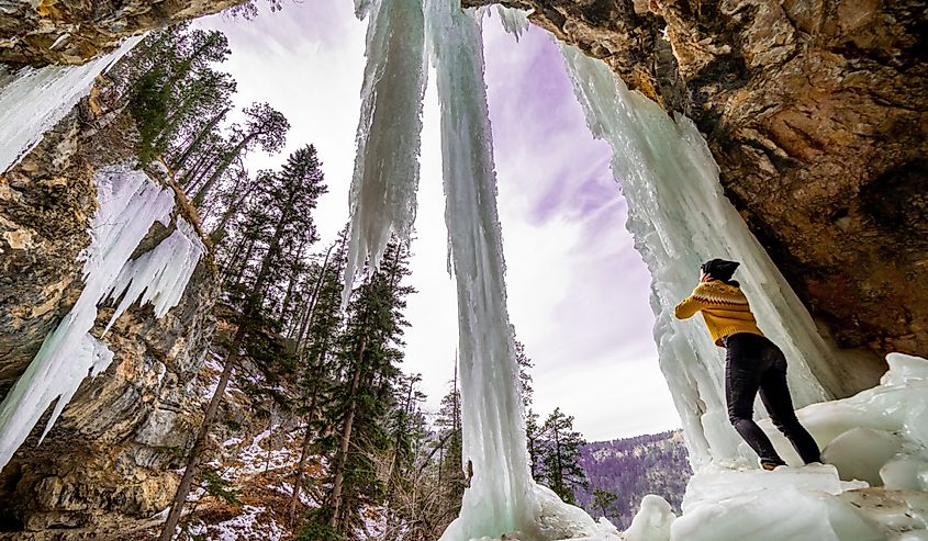 Girl standing under frozen waterfall in Spearfish, South Dakota