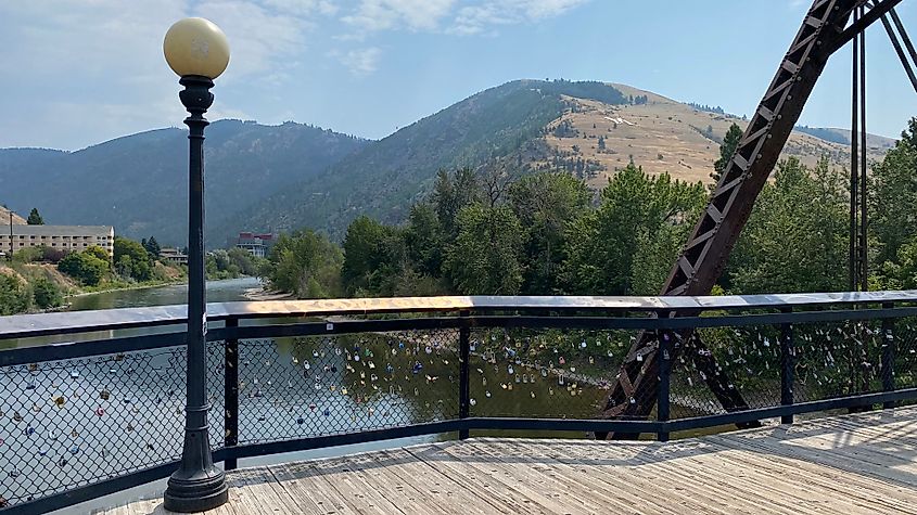 A lamppost and love locks on a boardwalk bridge overlooking the mountainous Clark Fork River valley of Missoula, MT.