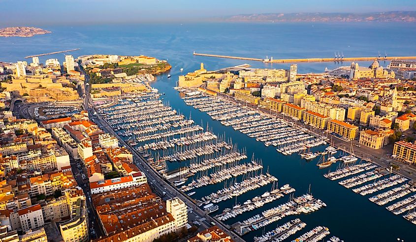 Scenic aerial view of coastal area of Marseille overlooking Old Port with moored yachts on background of blue water of Gulf of Lion in autumn, France.