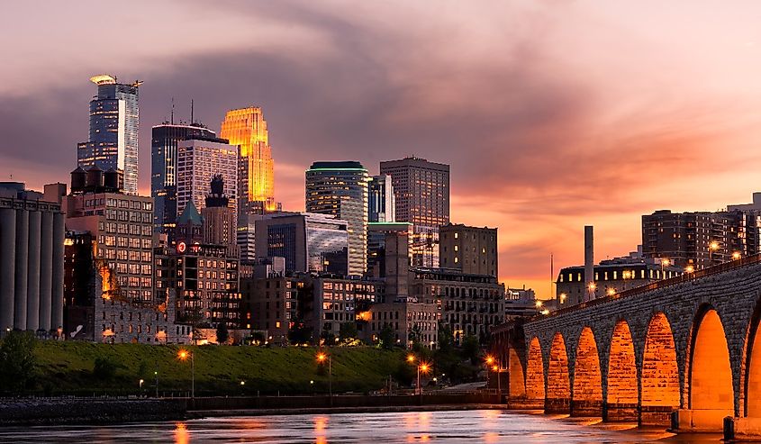 View of Minneapolis, Minnesota at dusk with red sun coming through bridge and buildings with cityscape