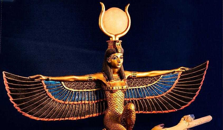 Egyptian goddess Isis kneeling with traditional magic wand made with quartz, amethyst crystals, wood and feathers