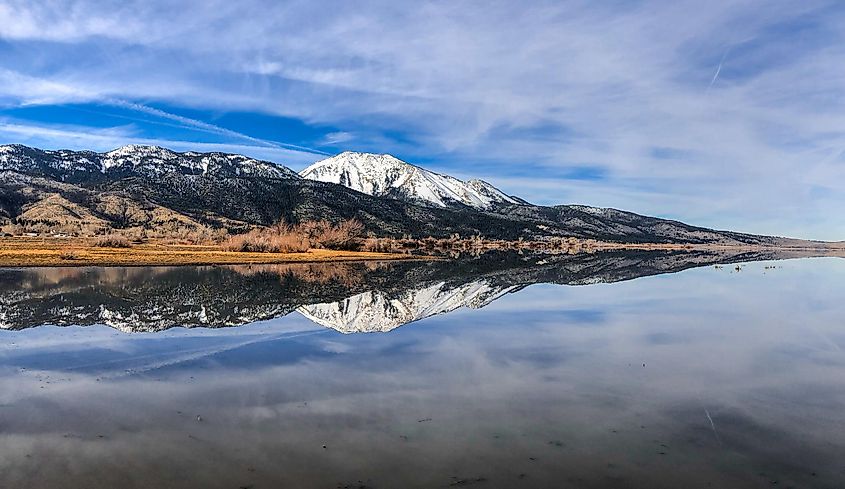 Mirror shot of Washoe Lake with a view towards Sierra Nevada Mountain Range and Mt Rose in the middle.