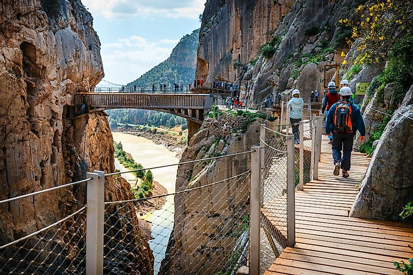 Visitors walking on the Caminito del Ray walkway along steep cliffs in Andalusia, Spain. 